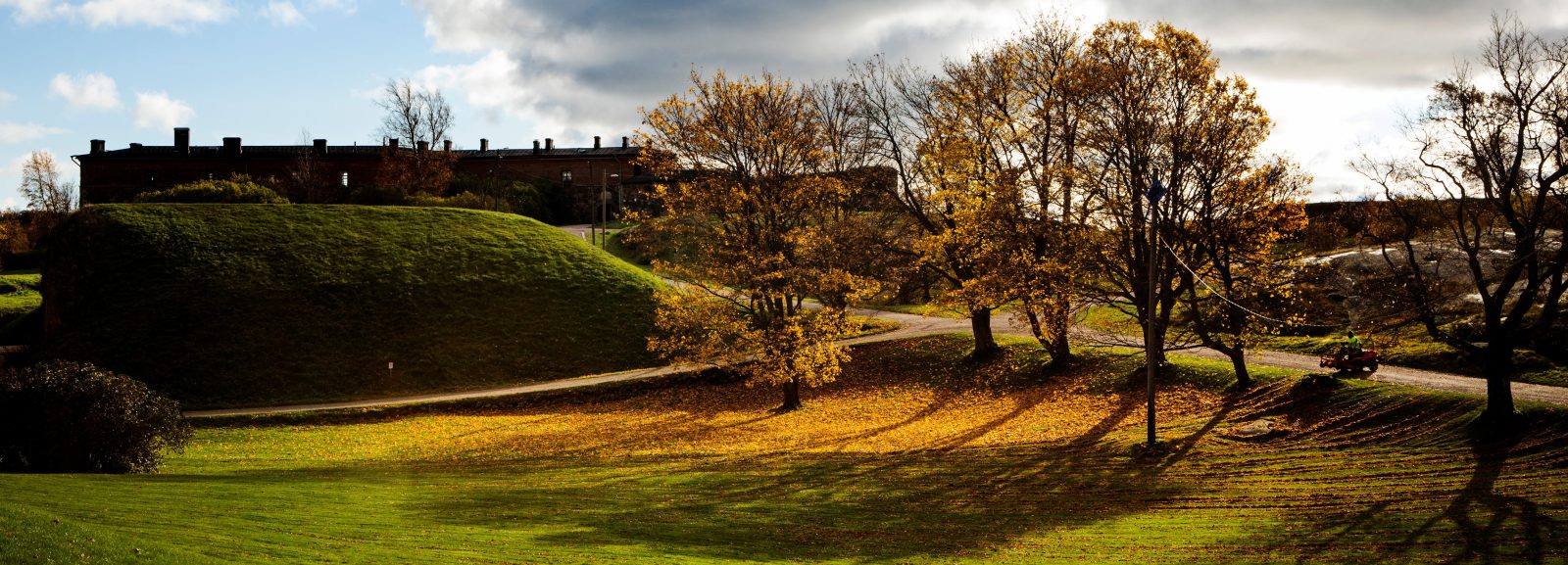 Syksyinen Suomenlinna, jossa näyy vihreä nurmikenttä ja värikkäät syksyiset puidenlehdet