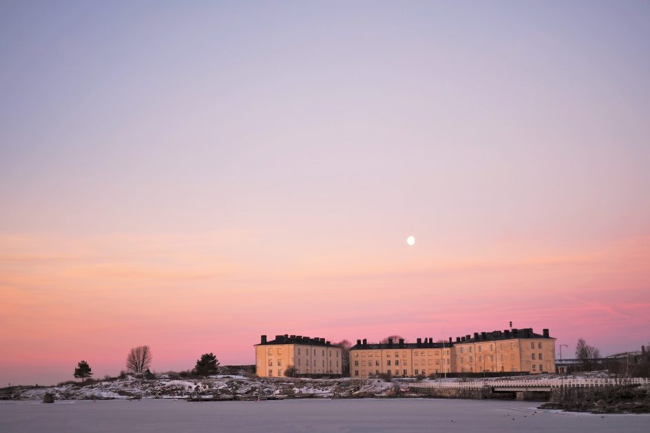 Länsimustasaaren asuinrakennukset auringonnousun aikaan. Kuu loistaa kirkkaana talojen yläpuolella