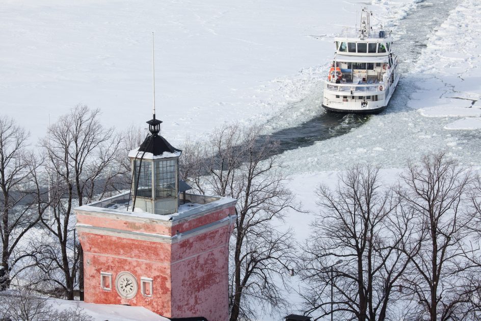 Ilmakuva, jossa näkyy rantakasarmin kellotorni ja suomenlinnan lautta talvisessa maisemassa